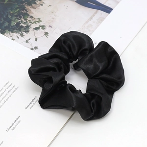 Elegant black satin scrunchie set on a minimalist fashion magazine style background