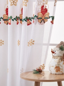 Detail of Christmas sheer curtain with red bells, green vines and gold snowflake embroidery