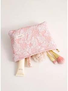 Pink embossed floral makeup bag with H & R brand label on a soft beige background