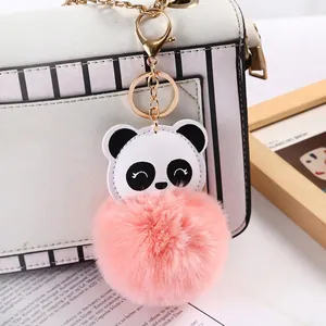 Cute panda pompom keychain with pink plush ball and gold lobster clasp on white handbag