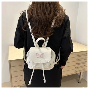 Close-up of white mini backpack featuring pink butterfly embroidery and floral accents
