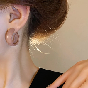 Close-up of model wearing chunky taupe enamel hoop earrings with a smooth C-shape finish