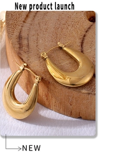 Detailed close-up of gold-plated U-shaped earrings on a natural wood surface background