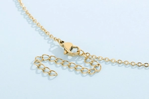 Macro detail of gold-plated stainless steel lobster clasp and adjustable extension chain