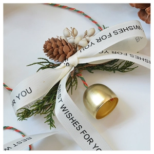 Detail of pine cone, golden bell, and white ribbon with Best Wishes for you text