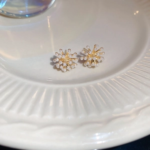 Détail de boucles d'oreilles perles dorées en forme de feu d'artifice sur plat