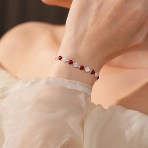 Detail of zircon and red heart bracelet on wrist with elegant silver finish