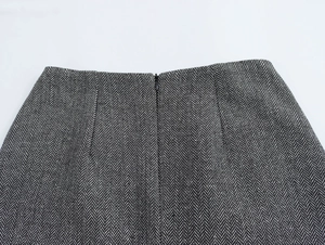 Detailed view of invisible zipper and herringbone wool texture on the gray skirt