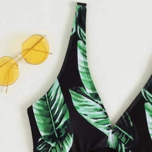Women's leaf print one-piece swimsuit with tropical pattern and stylish sunglasses