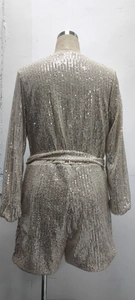 Detail of champagne gold sequin romper featuring a lace-up back and long sleeves on a mannequin