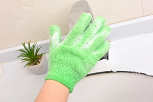 Green exfoliating scrub glove cleaning a chrome faucet in a bathroom setting