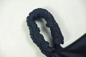 Detail der hochelastischen Raffung am Schultergurt eines schwarzen Slim-Fit Kleides