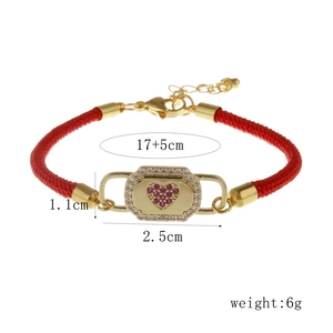 Macro shot of gold heart locket bracelet with purple zircon on a red braided cord