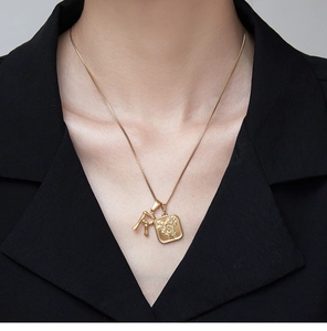 Macro view of 18K gold plated bamboo letter R and rose pendant necklace on model