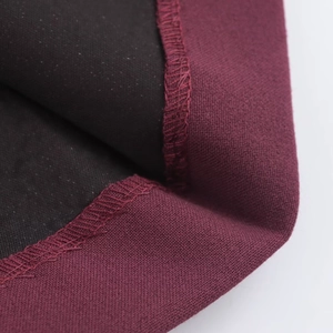Détail du tissu bordeaux avec doublure noire et coutures surjetées impeccables