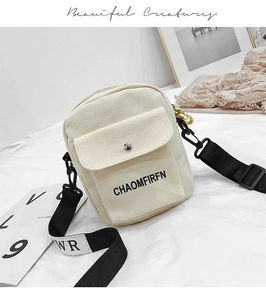 Detail of canvas crossbody bag with front snap pocket and printed logo strap