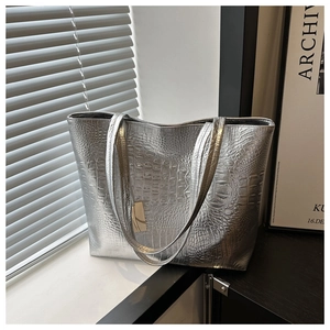 Silver crocodile pattern tote bag placed by a window with artistic shadow lighting