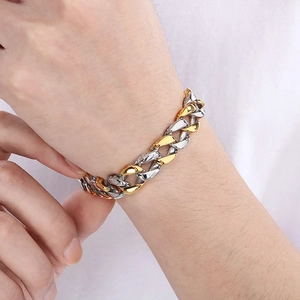 Detail of 11mm two-tone gold and silver Cuban link bracelet on male model wrist