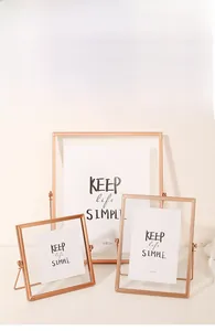 Detailed view of three minimalist rose gold metal photo frames with clear glass panels