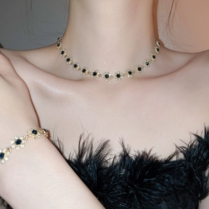 Detailed shot of sparkling flower pendant necklace and bracelet set in gold and black