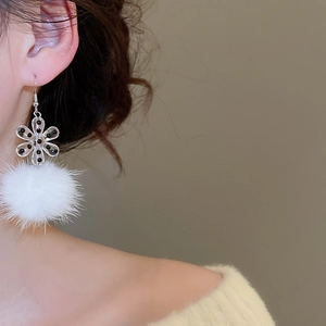 Detail of winter acrylic snowflake earrings with white plush pom poms and metal hooks