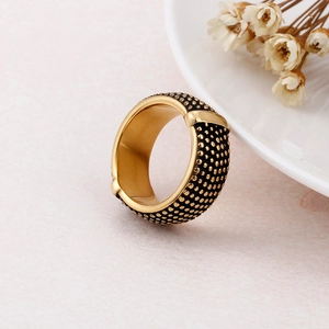 Detailed view of vintage gold textured ring with rivet pattern on pink marble surface
