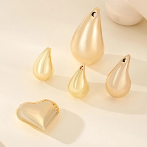 Detailed view of golden heart and teardrop shaped zircon pendants for DIY jewelry