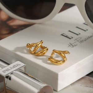 Minimalist gold stream-lined twisted hoop earrings displayed on a white jewelry box