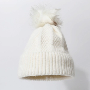 Thick white knit beanie with faux fur pom pom and ribbed texture for winter warmth