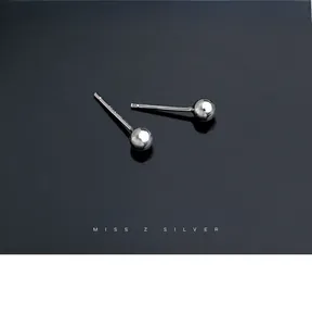 Macro shot of minimalist polished 925 sterling silver ball stud earrings on black surface