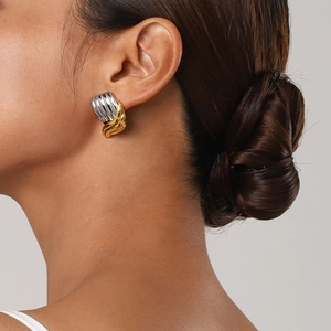 Close-up of dual-tone gold and silver textured geometric earrings worn by a model