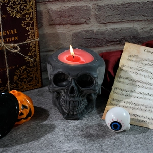 Gothic skull candle holder with lit red candle for Halloween table decoration