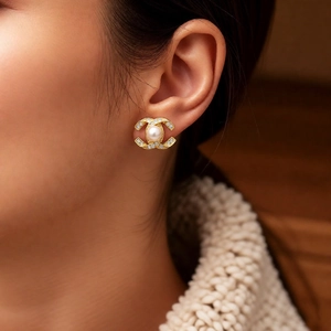 Detailed close-up of 14k gold plated earring with pearl and rhinestones on model
