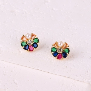 Macro shot of 18K gold floral earrings with colorful zircons and a small pearl accent