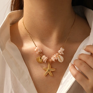 Detail of gold starfish and shell pendants on a beaded necklace worn by a model