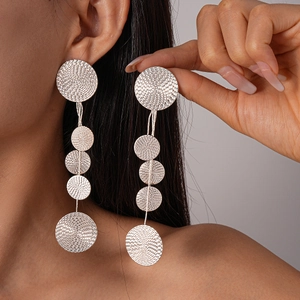 Macro detail of long silver fringe earrings with engraved circular metallic textures