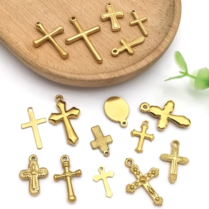 Collection of golden stainless steel cross pendants in various styles on a wooden tray