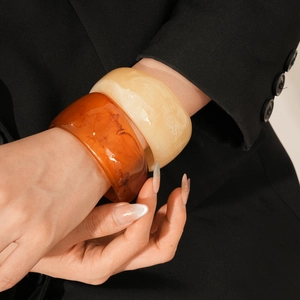 Detail of amber and cream resin chunky bracelets styled with a black blazer