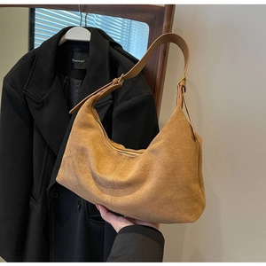 Detail of a brown suede hobo bag with adjustable strap and premium gold metal buckle