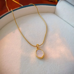 Macro view of gold oval shell pendant on a snake chain inside a jewelry gift box