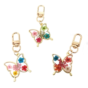 Detailed view of butterfly-shaped resin pendants with colorful dried flowers and gold clips