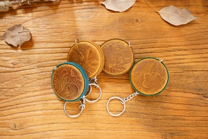 Top view of handmade crazy horse leather mini tape measures with embossed floral patterns