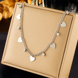 Detail of silver Cuban chain necklace with heart charms and clear crystal pendants