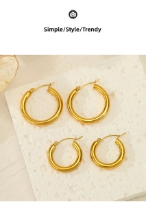 Polished gold hollow hoop earrings in two sizes displayed on white stone texture