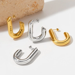 Macro detail of large gold and silver U-shaped chunky hoop earrings with mirror finish