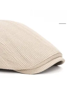Gros plan sur un béret beige à visière large pliable en tissu tricoté avec texture