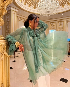 Detail view of a green sheer chiffon blouse with a large bow collar and long sleeves