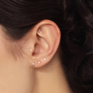 Close-up of four gold S925 silver stud earrings with cubic zirconia on a model's ear