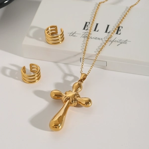 Detailed view of a gold cross necklace and triple-layered ring set on a jewelry box