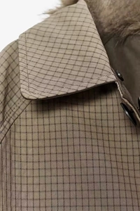 Close-up of brown plaid coat featuring a grey faux fur collar and black button detail